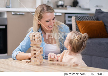having fun with child at weekend. mother helps to kid to develop her creativity by playing board game in living room smiling cheerful having fun with child at weekend. mother helps to kid to develop her creativity by playing board game in living room smiling cheerful 102026838