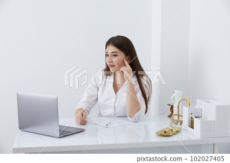 Portrait of female doctor talking to online patient on laptop screen sitting at clinic office desk giving online consultation for domestic health treatment Portrait of female doctor talking to online patient on laptop screen sitting at clinic office desk giving online consultation for domestic health treatment 102027405