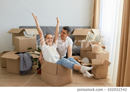 Indoor shot of happy couple having fun with cardboard boxes in new house at moving day, satisfied family with positive emotions surrounded with parcels with personal belongings. Indoor shot of happy couple having fun with cardboard boxes in new house at moving day, satisfied family with positive emotions surrounded with parcels with personal belongings. 102032542
