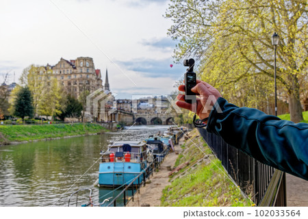 Young man filming river Avon in Bath, Somerset, England 102033564