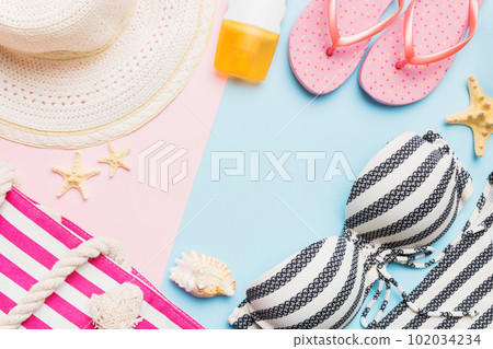 Woman swimwear and beach accessories flat lay top view on colored background Summer travel concept. bikini swimsuit, straw hat and seasheels. Copy space Top view Woman swimwear and beach accessories flat lay top view on colored background Summer travel concept. bikini swimsuit, straw hat and seasheels. Copy space Top view 102034234
