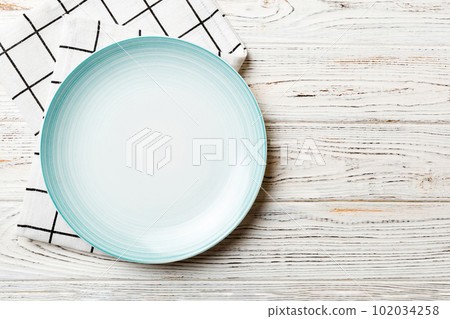 Top view on colored background empty round blue plate on tablecloth for food. Empty dish on napkin with space for your design 102034258