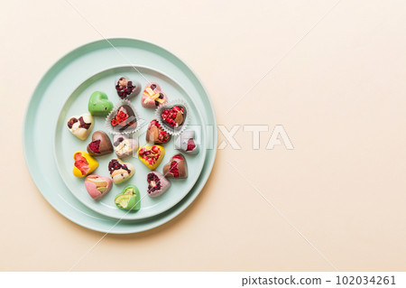 Plate with different chocolate on colored background. Assortment of fine chocolates top view vith copy space Health and obesity concept 102034261