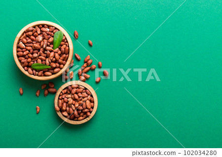 Fresh healthy peanuts in bowl on colored table background. Top view Healthy eating bertholletia concept. Super foods 102034280