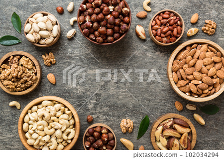 mixed nuts in wooden bowl. Mix of various nuts on colored background. pistachios, cashews, walnuts, hazelnuts, peanuts and brazil nuts 102034294
