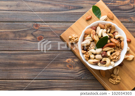 mixed nuts in bowl. Mix of various nuts on colored background. pistachios, cashews, walnuts, hazelnuts, peanuts and brazil nuts 102034303