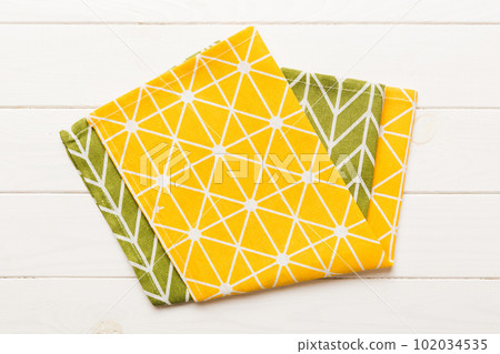 top view with yellow empty kitchen napkin isolated on table background. Folded cloth for mockup with copy space, Flat lay. Minimal style top view with yellow empty kitchen napkin isolated on table background. Folded cloth for mockup with copy space, Flat lay. Minimal style 102034535