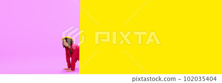 News, journalism. Young girl in stylish clothes peeking out vivid yellow and pink background. Pop art photography. News, journalism. Young girl in stylish clothes peeking out vivid yellow and pink background. Pop art photography. 102035404