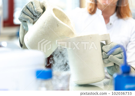 Female researcher doing laboratory research with liquid nitrogen in scientific laboratory, concept of pharmaceutical environment Female researcher doing laboratory research with liquid nitrogen in scientific laboratory, concept of pharmaceutical environment 102036733