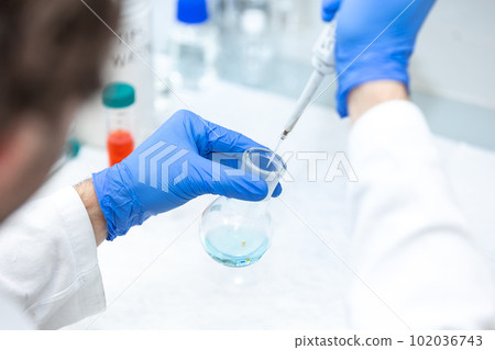 Female researcher with dropper dripping liquid into a test tube in scientific laboratory, concept of pharmaceutical environment Female researcher with dropper dripping liquid into a test tube in scientific laboratory, concept of pharmaceutical environment 102036743