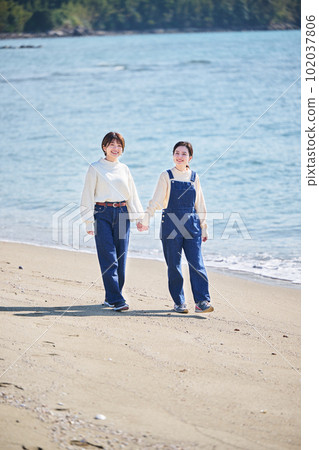 好年輕的女人和朋友手拉手走在沙灘上 好年輕的女人和朋友手拉手走在沙灘上 102037806
