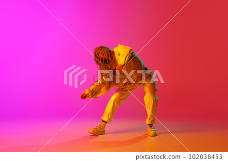 One young professional hip-hop dancer wearing stylish clothes moving with inspiration over gradient pink background in neon light One young professional hip-hop dancer wearing stylish clothes moving with inspiration over gradient pink background in neon light 102038453