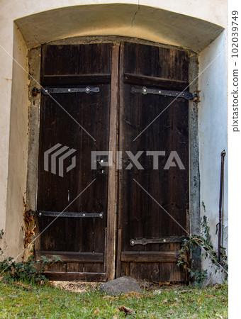 The old door in the wall is leaning against a boulder. The old door in the wall is leaning against a boulder. 102039749