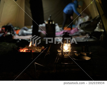 Tent interior and figures beyond lamps and bonfires 102039934