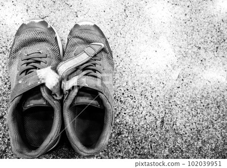 pair of worn out children's sneakers with scuffs damaged straps. 102039951