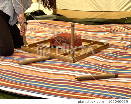 A woman assembling a kotatsu in a tent A woman assembling a kotatsu in a tent 102040019