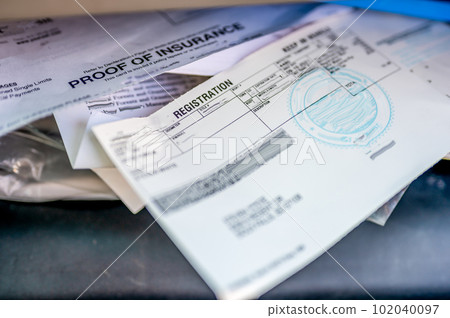 Proof of insurance and vehicle registration documents in the glove compartment of a car.  102040097