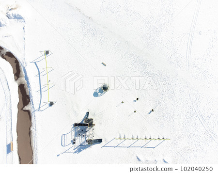 Aerial overhead drone view of school playground equipment covered in snow. 102040250