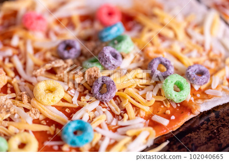 Pizza made by a child with cereal, cheese, and sauce. Pizza made by a child with cereal, cheese, and sauce. 102040665