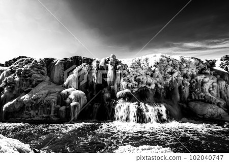 Sioux Falls Park waterfall with ice and snow. Cascading snowmelt water pouring over the top into a pool of standing water. 102040747