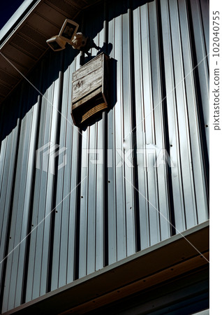 Wooden bat house on white corrugated tin barn 102040755