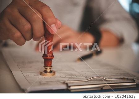businessman hand stamping approved on certificate document contract in office. Lawyer stamping permit on paperwork at wooden desk. 102041622