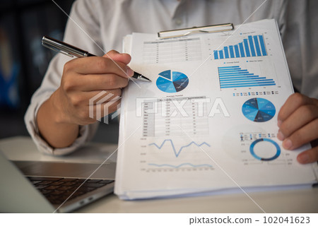 businessmen pen pointing to graphs and report on table, financial accounts, market economy. businessmen pen pointing to graphs and report on table, financial accounts, market economy. 102041623