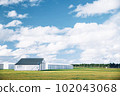 Steel barn on a farm with cloudy blue sky. 102043068