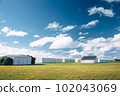Steel barn on a farm with cloudy blue sky. 102043069
