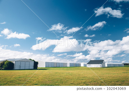 Steel barn on a farm with cloudy blue sky. 102043069