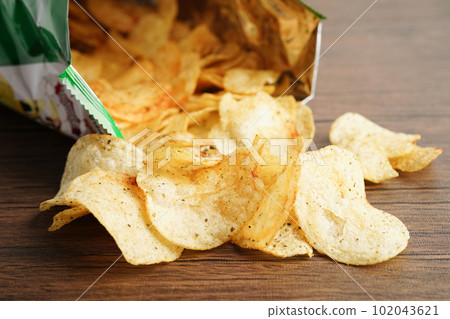 Potato chips in open bag, delicious BBQ seasoning spicy for crips, thin slice deep fried snack fast food in open bag. 102043621