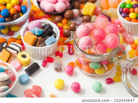Pink lollipop candies in jar with various milk chocolate and jelly gums candies Pink lollipop candies in jar with various milk chocolate and jelly gums candies 102043647