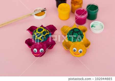 Two handmade craft a turtle toy from a cardboard egg tray. Zero waste concept. 102044665