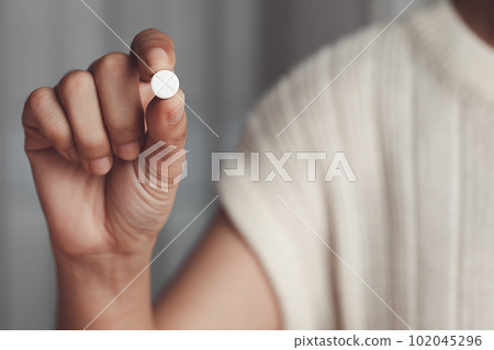 Asian woman's hand holding a white pill for medical and healthcare concept. Asian woman's hand holding a white pill for medical and healthcare concept. 102045296