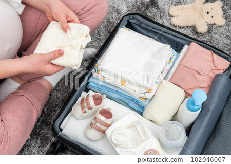 Pregnant woman packing suitcase for maternity hospital at home Pregnant woman packing suitcase for maternity hospital at home 102046007