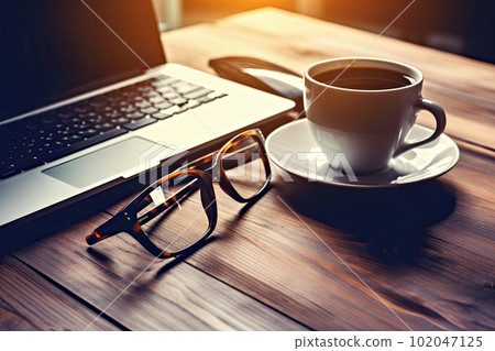 A laptop, coffee and glasses on a wooden desk A laptop, coffee and glasses on a wooden desk 102047125