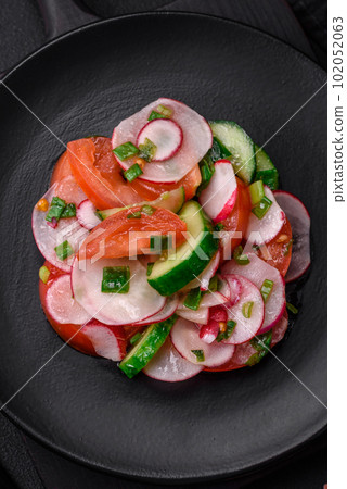 Delicious vegan salad of fresh vegetables of tomatoes, cucumbers and radishes 102052063
