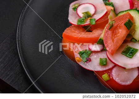 Delicious vegan salad of fresh vegetables of tomatoes, cucumbers and radishes 102052072