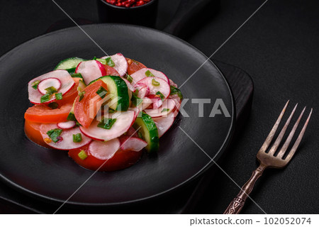 Delicious vegan salad of fresh vegetables of tomatoes, cucumbers and radishes 102052074
