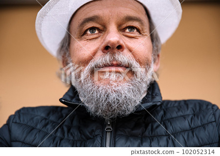 Portrait of a confident, handsome, mature man, pensioner, grandfather near his house, anti aging activities 102052314