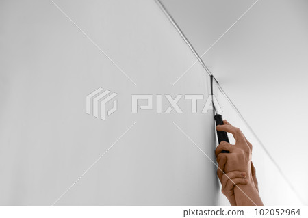 Repairman installing white stretch ceiling in room, closeup 102052964