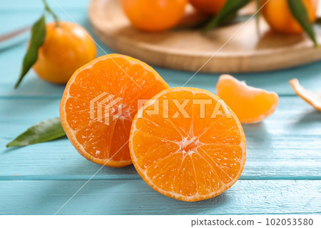 Cut fresh ripe tangerines on light blue table 102053580