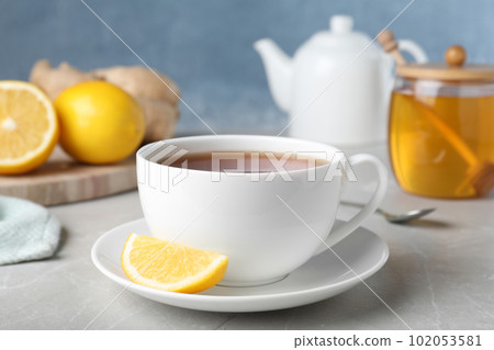 Fresh tea with honey and lemon on light grey marble table, closeup 102053581