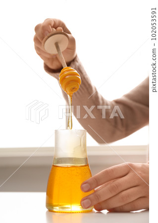 Woman with honey and dipper at white table, closeup Woman with honey and dipper at white table, closeup 102053591