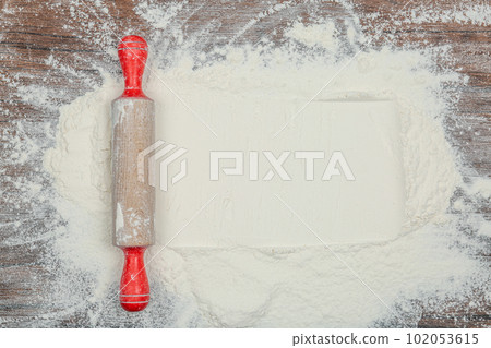 Flour and rolling pin on wooden table, top view. Space for text 102053615