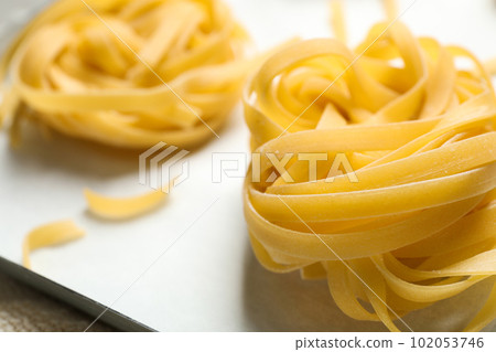 Raw tagliatelle pasta in baking pan, closeup view Raw tagliatelle pasta in baking pan, closeup view 102053746