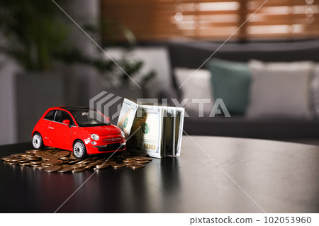 Miniature automobile model and money on table indoors, space for text. Car buying Miniature automobile model and money on table indoors, space for text. Car buying 102053960