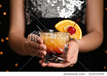 Woman with glass of Tequila Sunrise, closeup. Delicious alcoholic cocktail Woman with glass of Tequila Sunrise, closeup. Delicious alcoholic cocktail 102053995