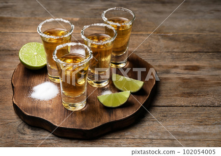 Mexican Tequila shots, lime and salt on wooden table Mexican Tequila shots, lime and salt on wooden table 102054005