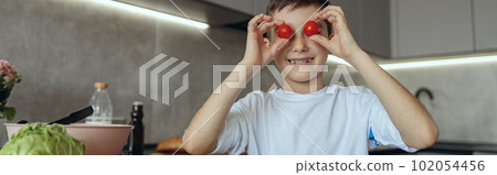 Portrait of small teen Caucasian boy cooking in kitchen and playing with vegetables. Portrait of small teen Caucasian boy cooking in kitchen and playing with vegetables. 102054456